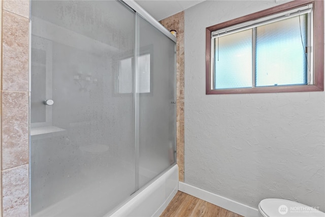 9811 NE 152nd Ave, Vancouver, WA 98682 - full bath with baseboards, wood finished floors, shower / bath combination with glass door, and toilet