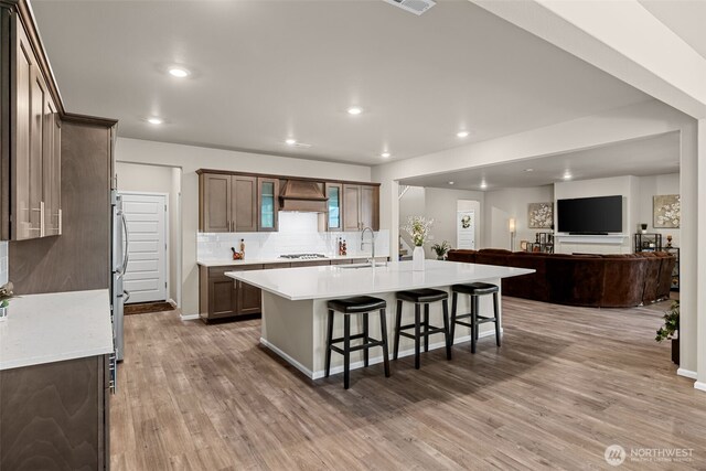32832 SE Stevens St, Black Diamond, WA 98010 - kitchen featuring a sink, a breakfast bar area, wood finished floors, gas stovetop, and custom exhaust hood