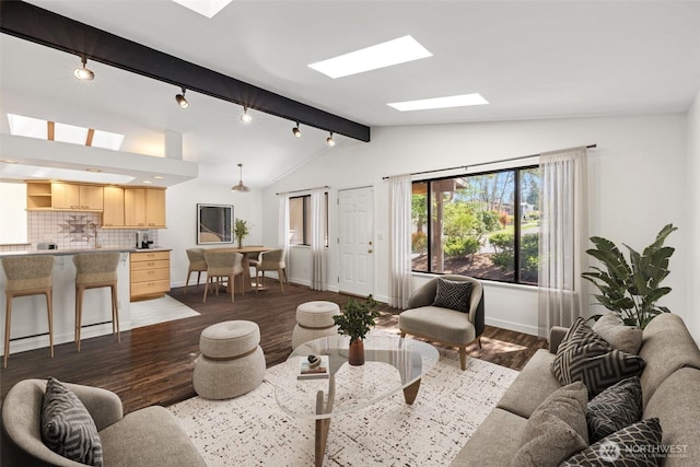 living room with a skylight, dark wood-style floors, baseboards, and rail lighting