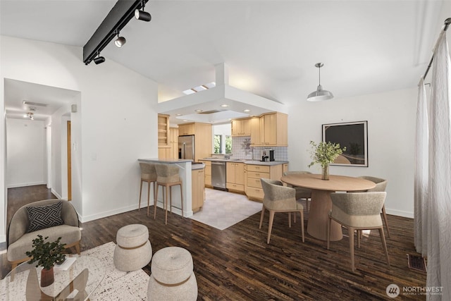 dining room featuring vaulted ceiling, rail lighting, wood finished floors, baseboards, and recessed lighting