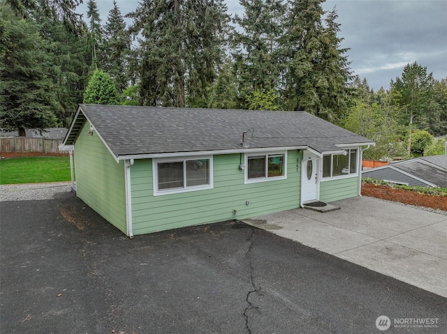 view of front of property with a shingled roof, a patio, fence, and driveway