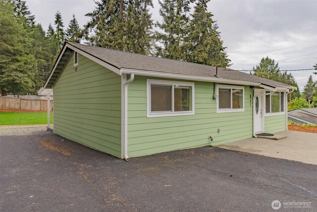 view of front of property with a patio area, fence, and a shingled roof