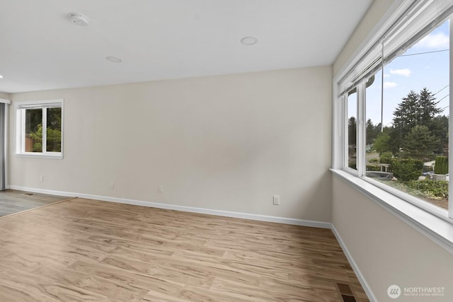 spare room featuring baseboards, light wood-style floors, and a smoke detector