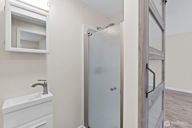 full bath featuring a stall shower, wood finished floors, and baseboards