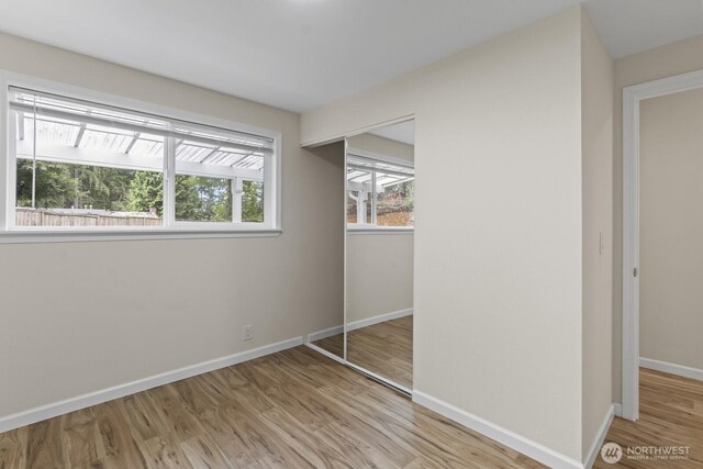 unfurnished bedroom with a closet, wood finished floors, and baseboards