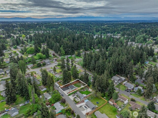 aerial overview of property's location with a heavily wooded area, property boundaries highlighted, and nearby suburban area