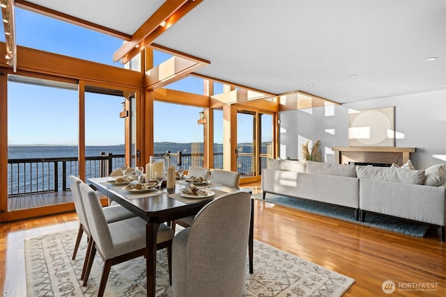 3103 Alki Ave SW, Seattle, WA 98116 - dining area featuring wood finished floors, a water view, a fireplace, and floor to ceiling windows