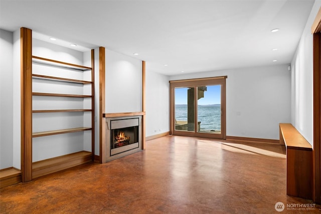 3103 Alki Ave SW, Seattle, WA 98116 - unfurnished living room featuring a lit fireplace, concrete flooring, recessed lighting, baseboards, and a water view