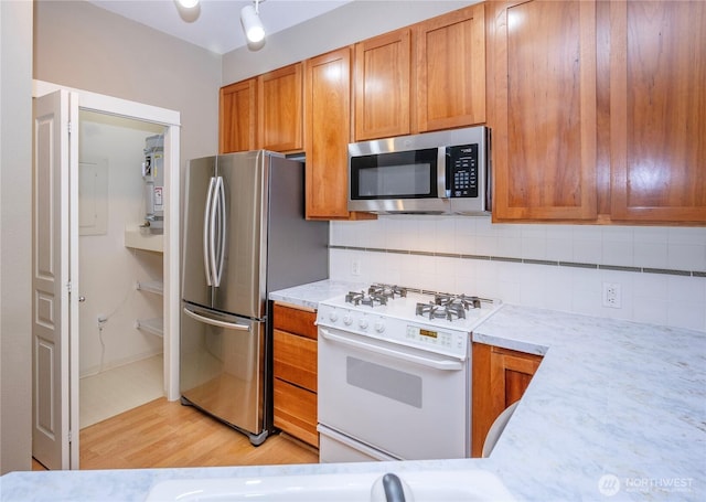 kitchen with brown cabinets, light countertops, backsplash, and stainless steel appliances