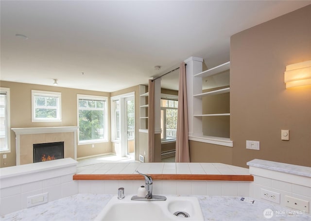 kitchen featuring a sink, light countertops, open shelves, and a tiled fireplace
