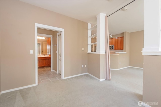 unfurnished room with a sink, light colored carpet, and baseboards