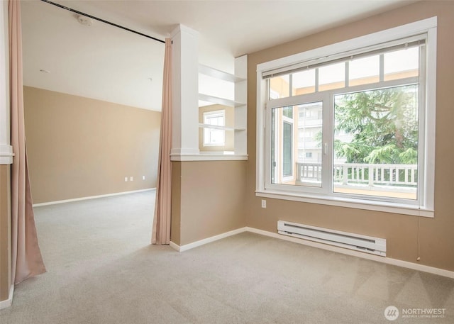 carpeted spare room featuring a baseboard heating unit and baseboards