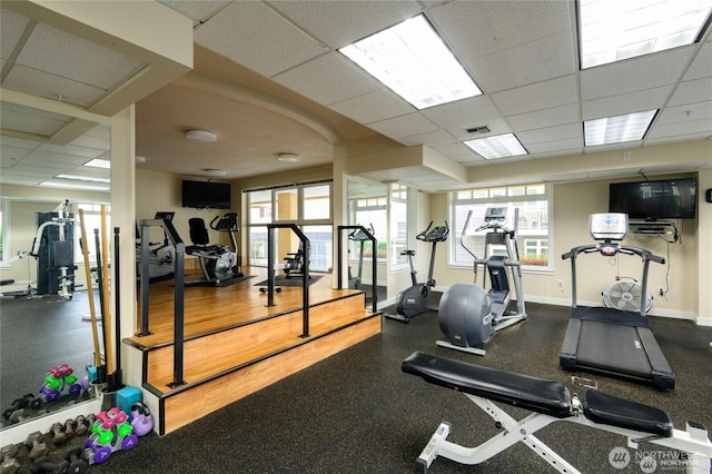 gym featuring visible vents, a drop ceiling, baseboards, and a wealth of natural light