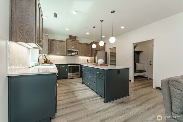 2302 S Royal Ct, Ridgefield, WA 98642 - kitchen with stainless steel appliances, a sink, light wood-type flooring, backsplash, and light countertops