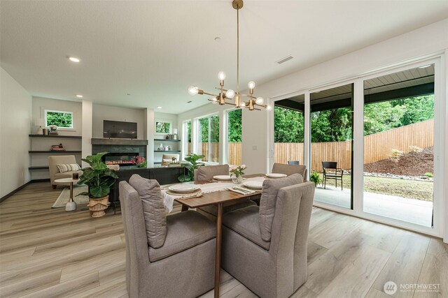 2302 S Royal Ct, Ridgefield, WA 98642 - dining space with a glass covered fireplace, a chandelier, light wood finished floors, and recessed lighting