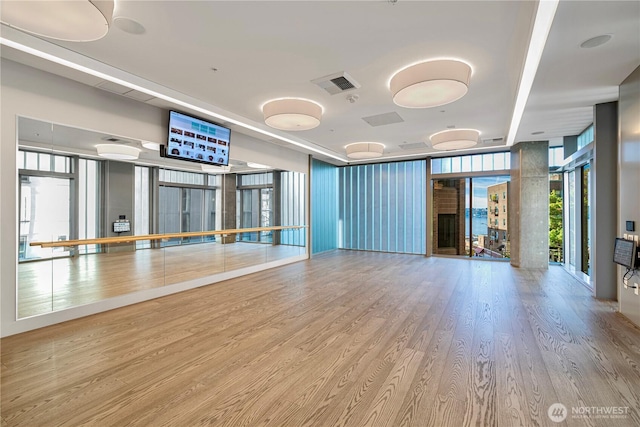 workout room featuring wood finished floors, visible vents, and a wall of windows