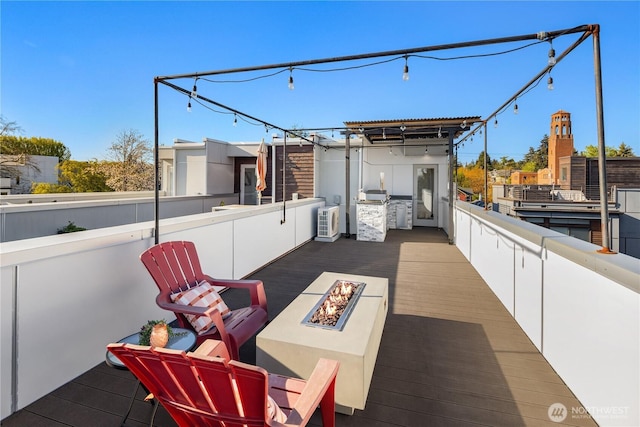 view of patio with an outdoor kitchen, an outdoor fire pit, and a deck