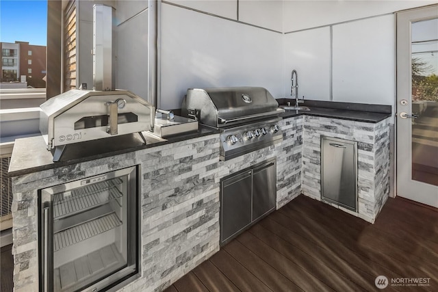 view of patio / terrace with wine cooler, a sink, an outdoor kitchen, a deck, and area for grilling