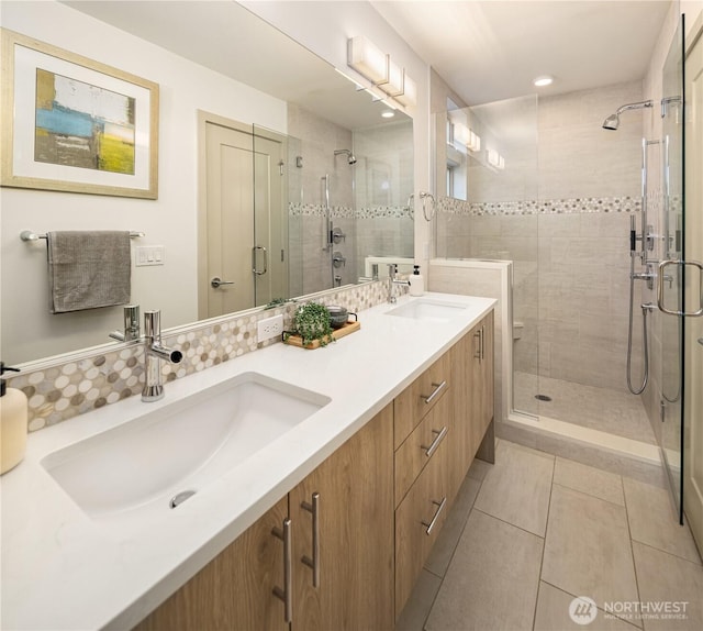 bathroom featuring double vanity, a shower stall, tile patterned floors, and a sink