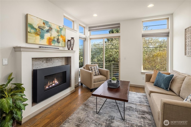 living room with wood finished floors, a tile fireplace, and recessed lighting
