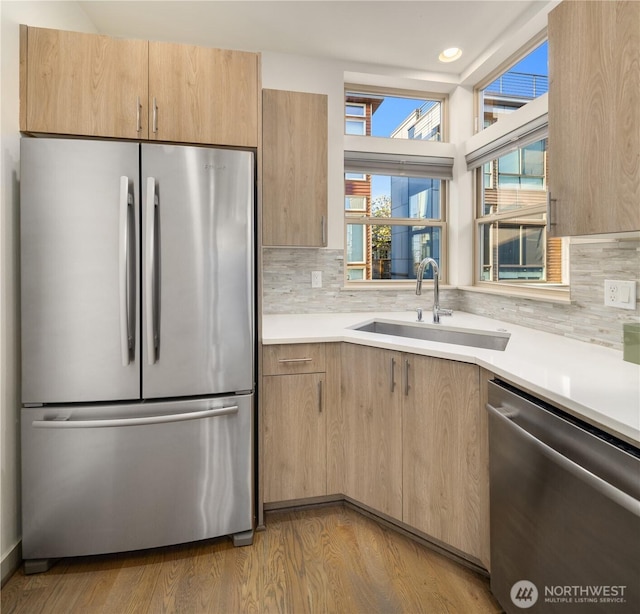kitchen featuring light countertops, decorative backsplash, stainless steel appliances, and a sink