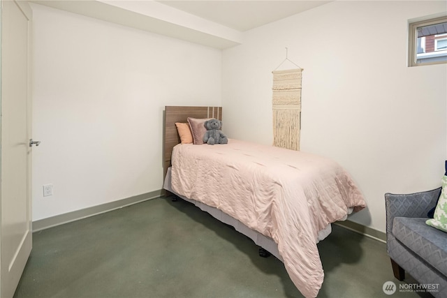 bedroom featuring concrete flooring and baseboards