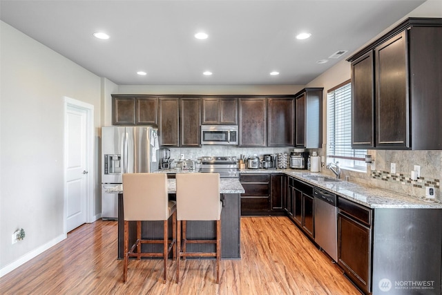 15504 82nd Ave E, Puyallup, WA 98375 - kitchen with light wood finished floors, stainless steel appliances, dark brown cabinets, decorative backsplash, and light stone countertops