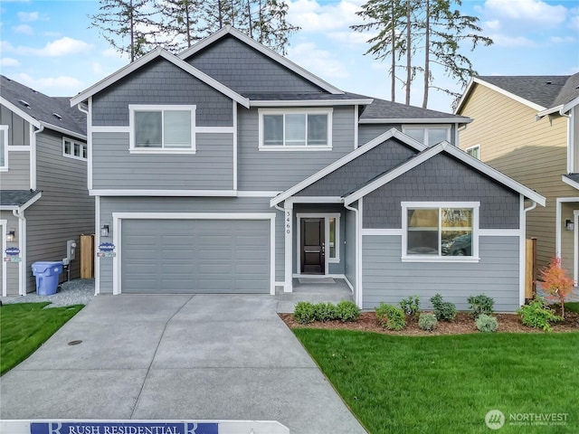 craftsman-style home featuring an attached garage, driveway, and a front yard