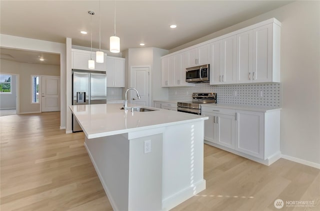 kitchen featuring decorative backsplash, light wood-style floors, stainless steel appliances, and a sink