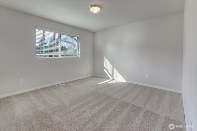 spare room featuring carpet floors, visible vents, and baseboards