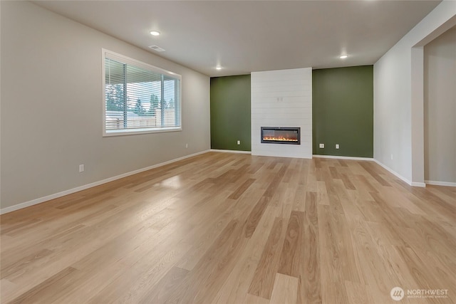 unfurnished living room featuring light wood-type flooring, baseboards, a large fireplace, and recessed lighting