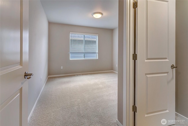 empty room with carpet floors, visible vents, and baseboards