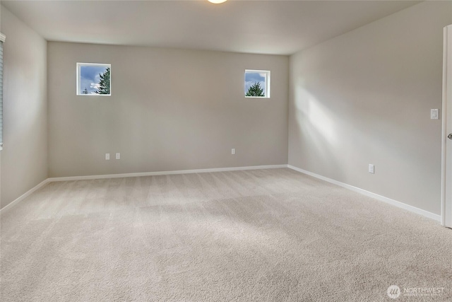 spare room featuring baseboards, light carpet, and plenty of natural light