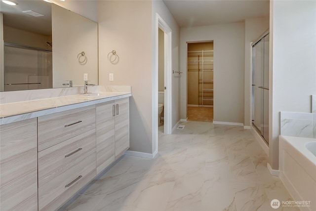 bathroom with vanity, marble finish floor, a stall shower, and toilet