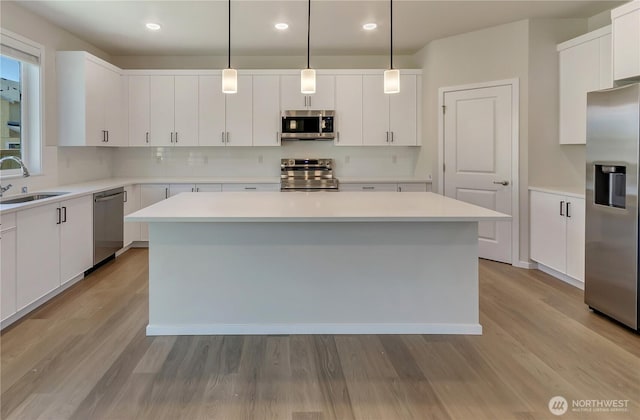 18213 35th Avenue Ct E, Tacoma, WA 98446 - kitchen with appliances with stainless steel finishes, a kitchen island, backsplash, recessed lighting, and wood finished floors