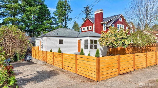 exterior space with a shingled roof and a fenced front yard