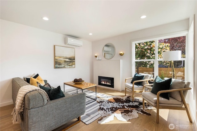 living room with light wood finished floors, a glass covered fireplace, recessed lighting, and a wall mounted air conditioner