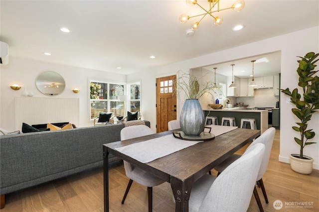 dining room featuring a wall mounted AC, a chandelier, recessed lighting, and light wood-style floors