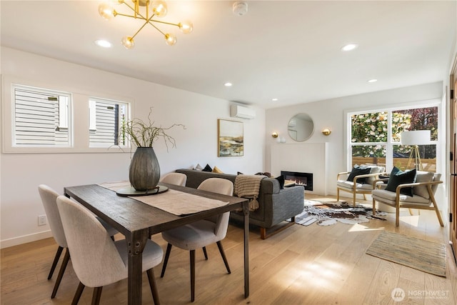 dining area with light wood finished floors, a glass covered fireplace, an inviting chandelier, recessed lighting, and a wall mounted air conditioner