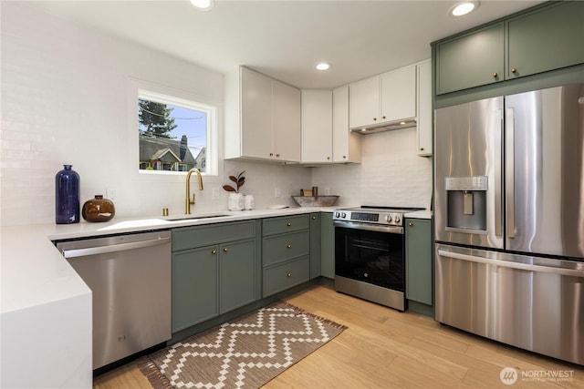 kitchen featuring light wood-style flooring, green cabinets, appliances with stainless steel finishes, and a sink