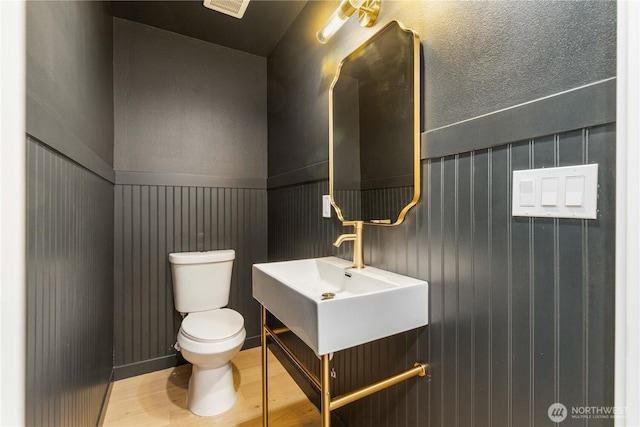 bathroom featuring wainscoting, wood finished floors, vanity, and toilet