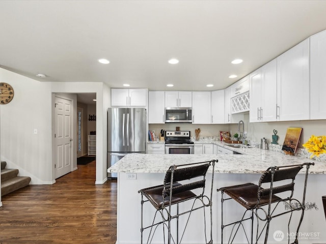17581 110th Ln SE Unit 3, Renton, WA 98055 - kitchen with appliances with stainless steel finishes, a sink, a peninsula, dark wood-style floors, and white cabinets