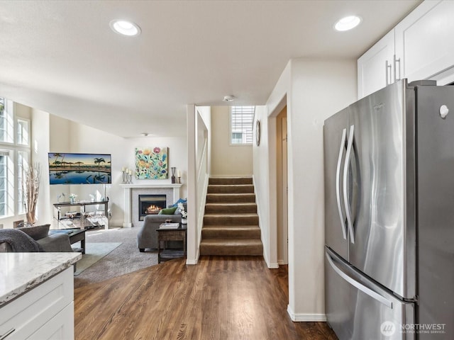 17581 110th Ln SE Unit 3, Renton, WA 98055 - kitchen featuring freestanding refrigerator, a warm lit fireplace, dark wood-style flooring, white cabinets, and light stone counters