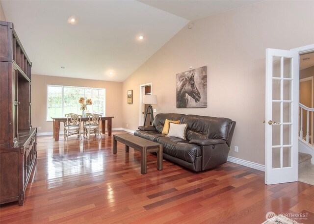 living room with vaulted ceiling, wood finished floors, and baseboards