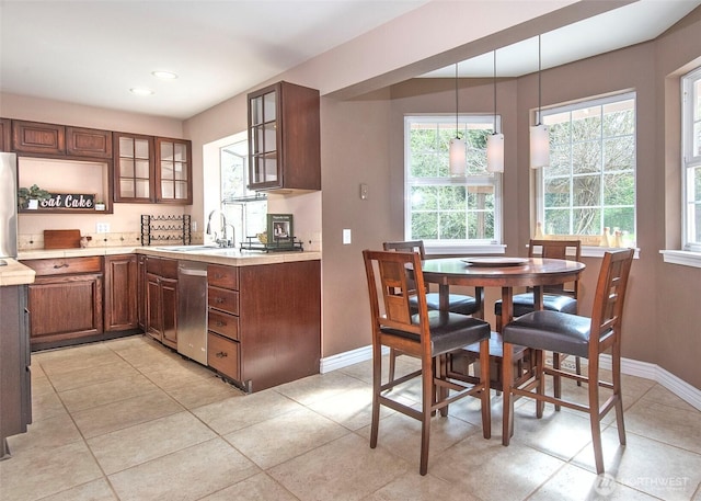 kitchen featuring glass insert cabinets, light countertops, a sink, and appliances with stainless steel finishes