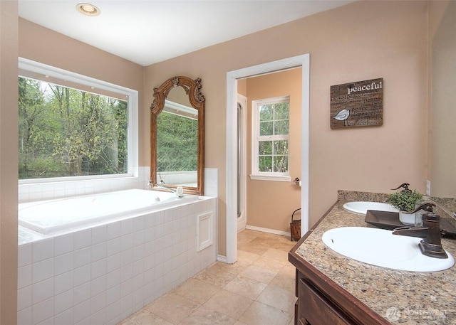 bathroom with a bath, baseboards, and a sink