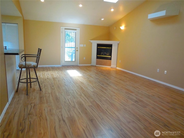 5036 Beach Way NE, Olympia, WA 98516 - unfurnished living room with wood finished floors, vaulted ceiling, a tiled fireplace, recessed lighting, and a skylight