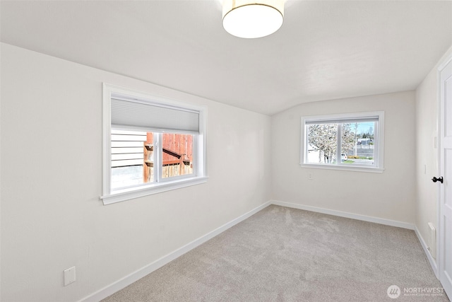 unfurnished room with baseboards, light colored carpet, and lofted ceiling
