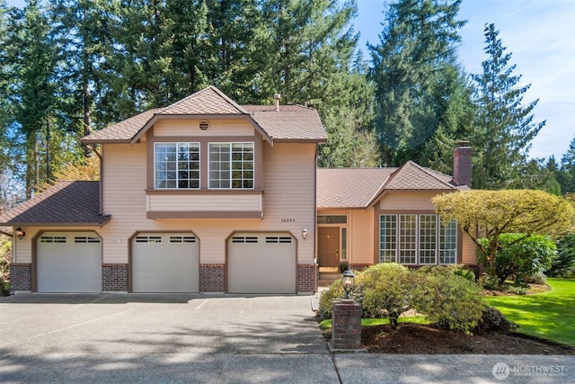 traditional home featuring an attached garage, aphalt driveway, and brick siding
