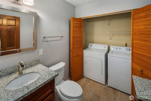 bathroom featuring washer and clothes dryer, toilet, wood finished floors, a closet, and vanity